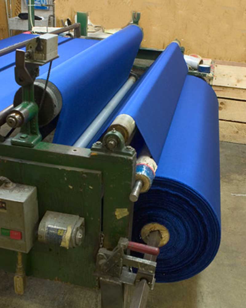 blue fabric on spools through a manufacturing machine